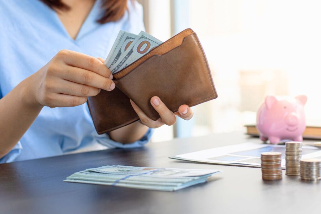 a girl is taking out money from a wallet representing how to fix bad money habits fast