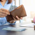 a girl is taking out money from a wallet representing how to fix bad money habits fast